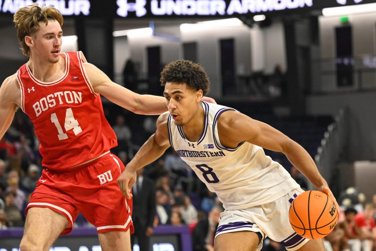 A basketball player brings the ball up the court as an opposing team member tries to defend. 