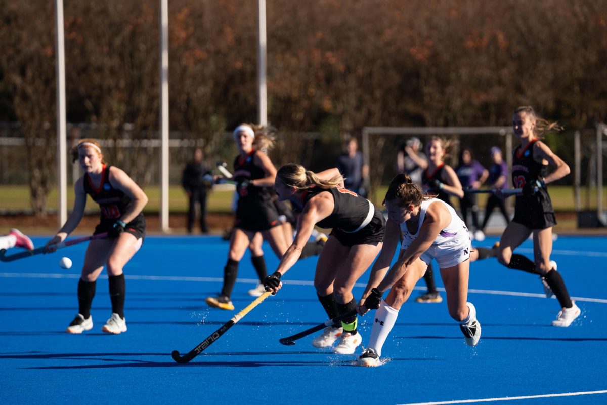 A player in a white jersey takes a shot as a player in a black jersey attempts to block it. 