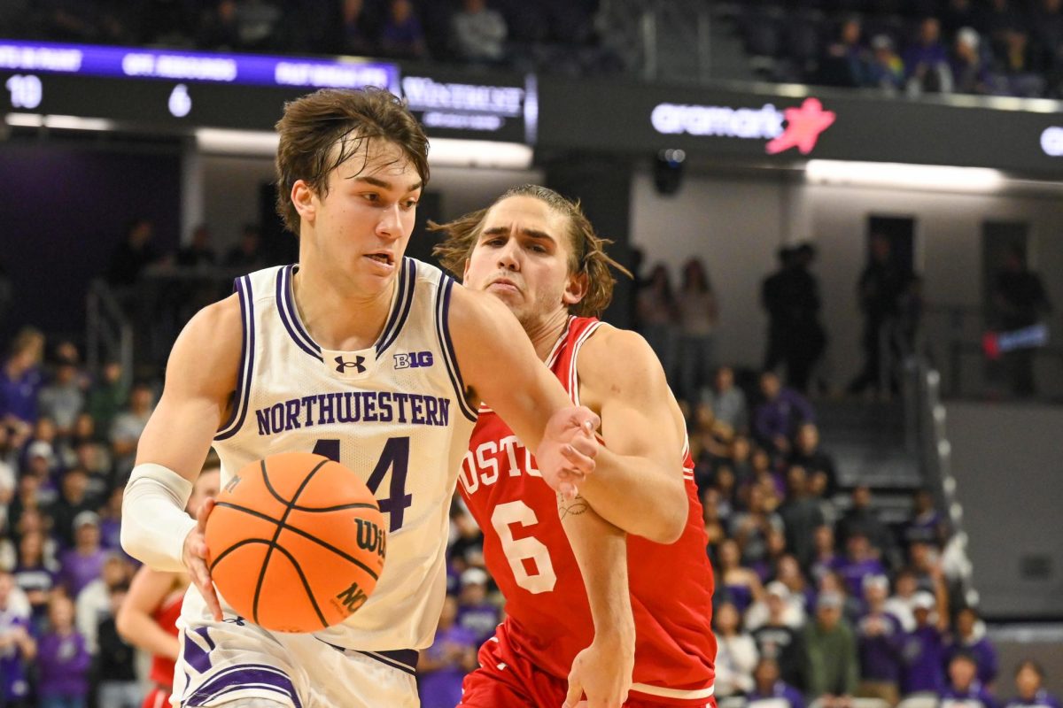 A basketball player dribbles down the court as an opposing team member attempts to defend. 