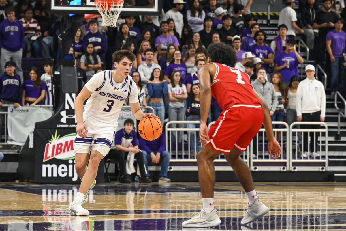 A basketball player with the ball stares down their defender. 