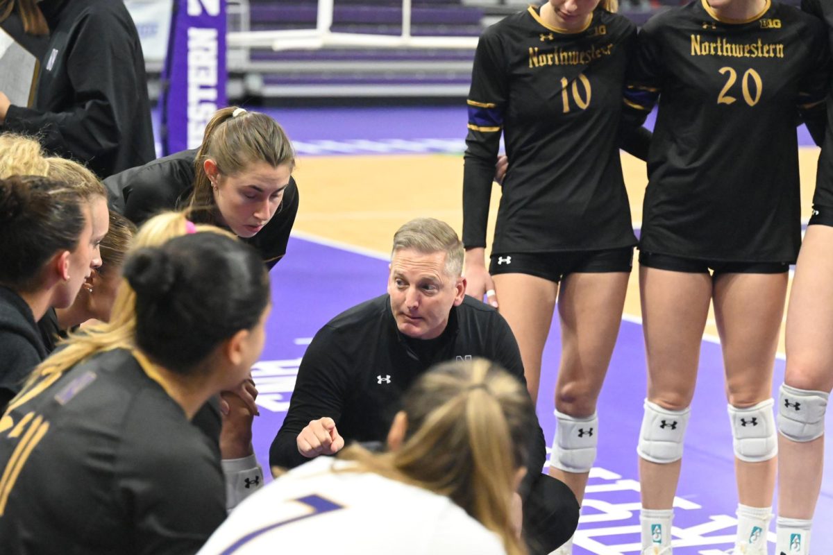Coach Tim Nollan speaks to NU players as they circle up off the court. 