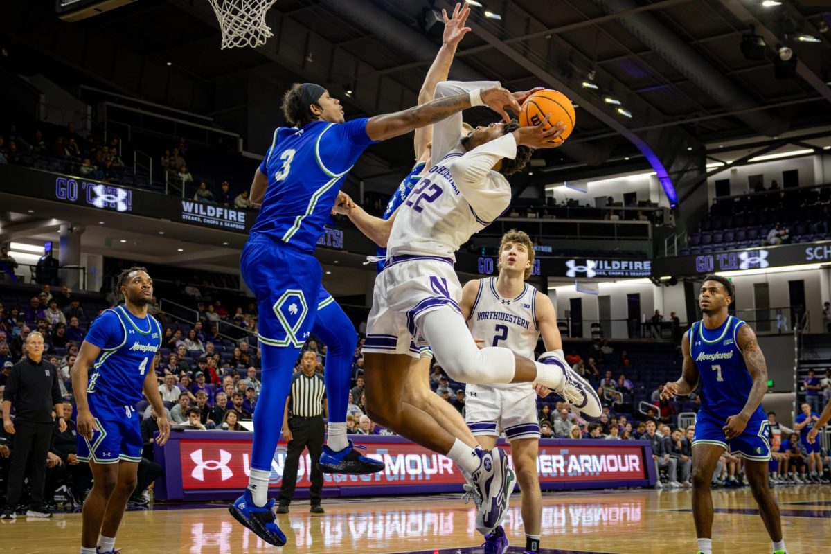 A player in a white jersey leaps during a layup attempt over a player in a blue jersey.