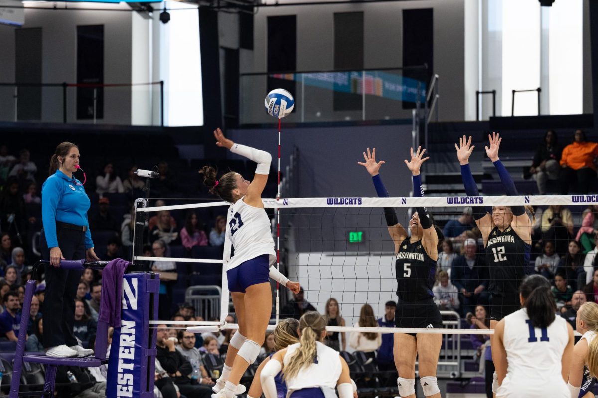 Rylen Reid hits the ball as two Washington players block the ball