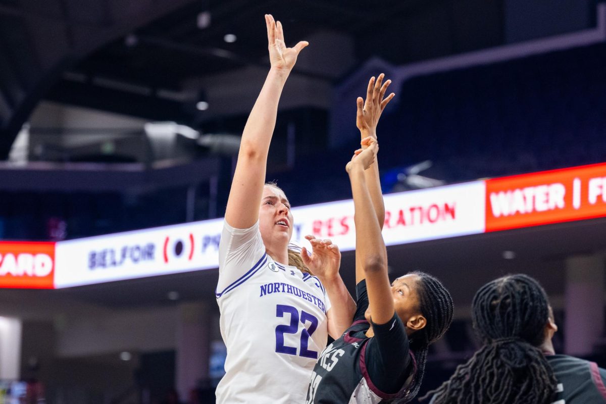 A player shoots over a jumping defender.