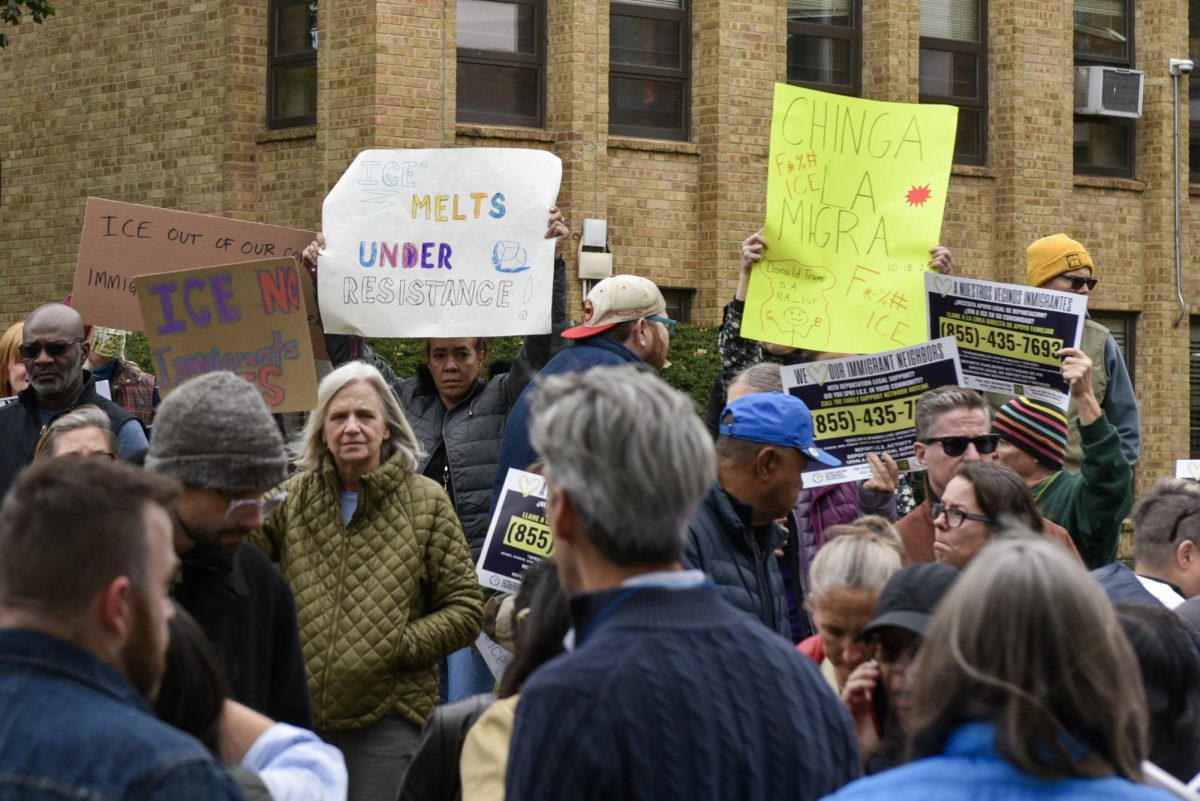 A large crowd of people hold signs above their heads and talk.