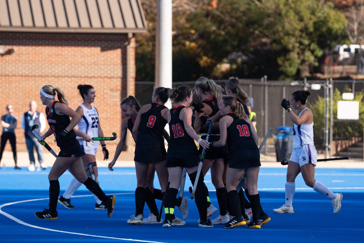 Players in black jerseys huddle in celebration. 
