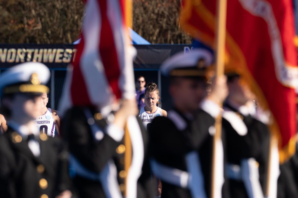 A player in a white jersey stands behind people carry flags.