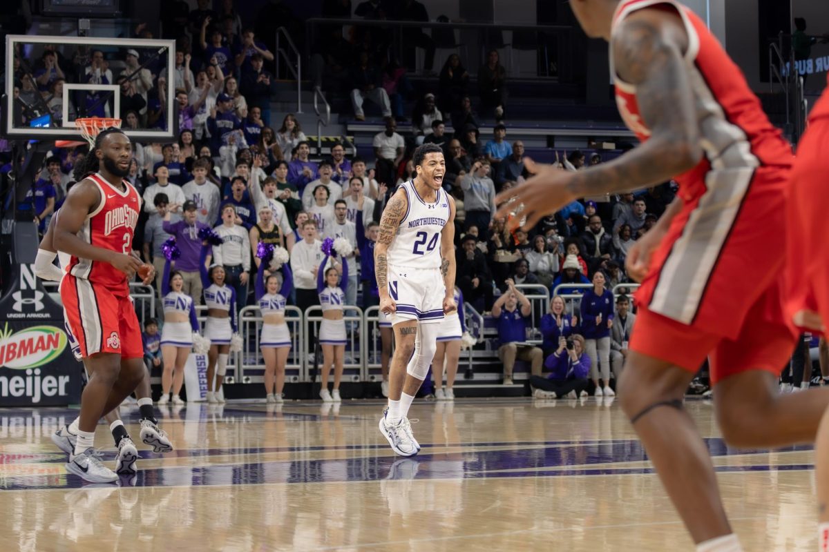 A Northwestern player yells in celebration near midcourt as the student section and cheerleaders erupt behind them, while Ohio State players turn back toward defense. 