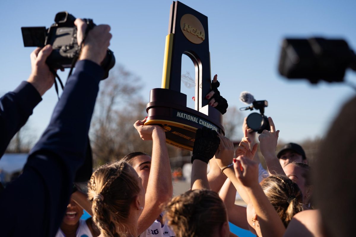A player surrounded by teammates hoists a trophy 