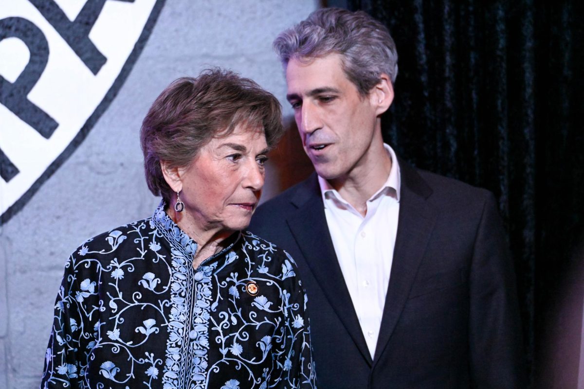 A person talks into another person’s ear on stage.