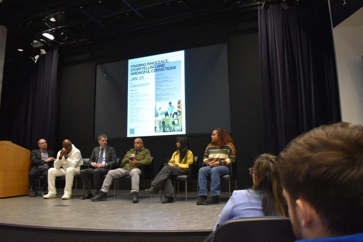 A stage of panelists sitting in chairs.