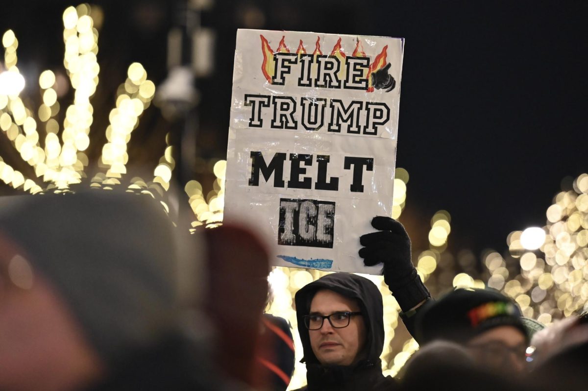 A person holds a sign that reads, &ldquo;Fire Trump Melt Ice.&rdquo;
