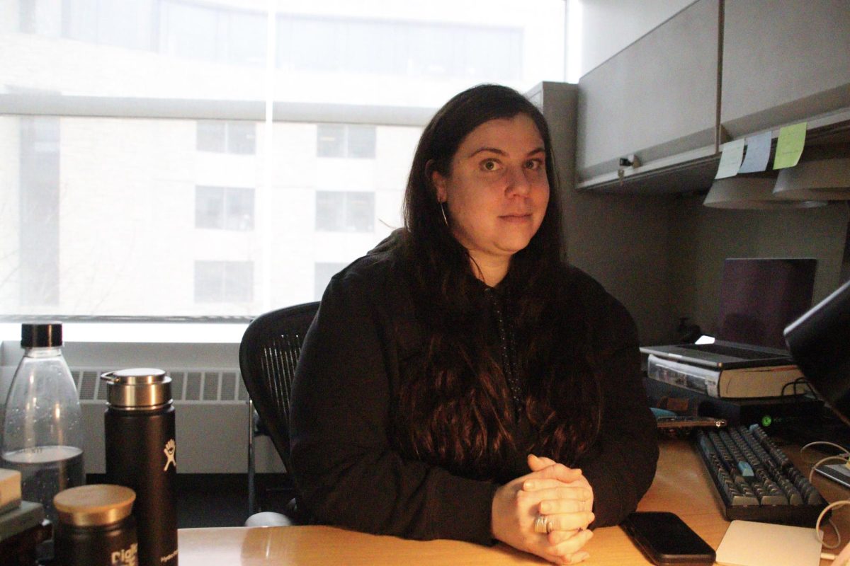 A person sits behind an office desk, silhouetted against a window.