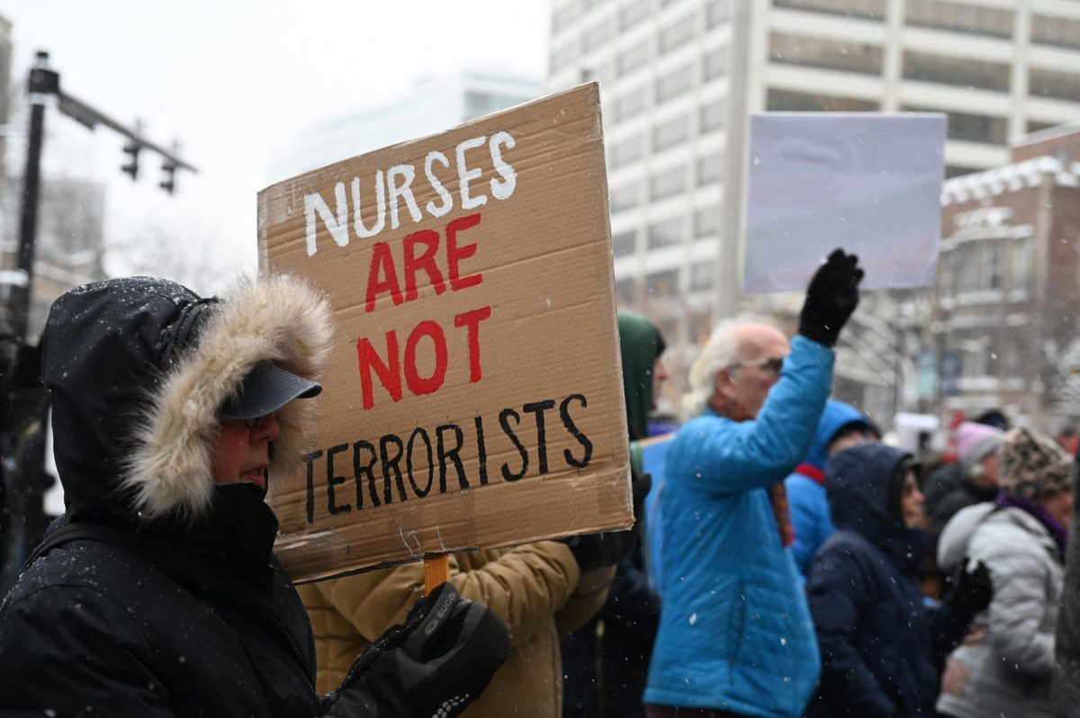 An attendee holds a sign that reads “Nurses Are Not Terrorists.”