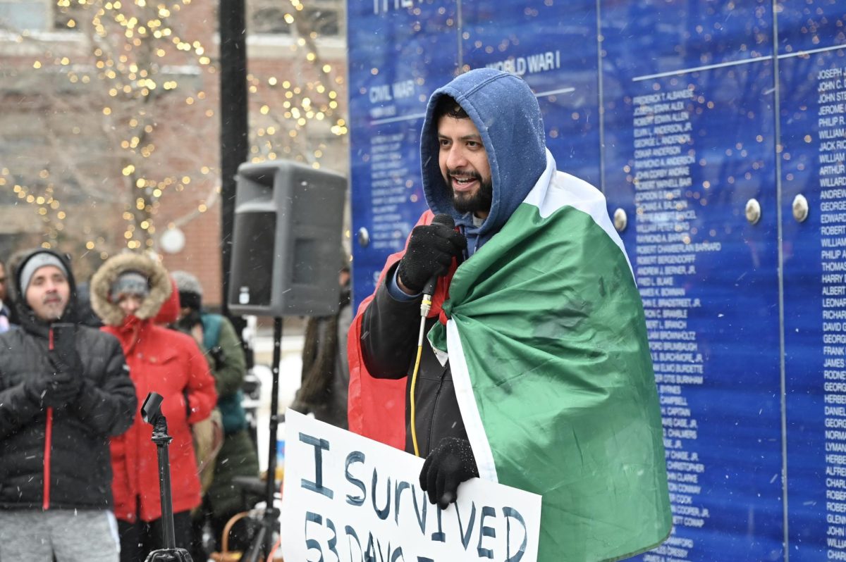 A person wrapped in a Mexican flag speaks into a microphone.