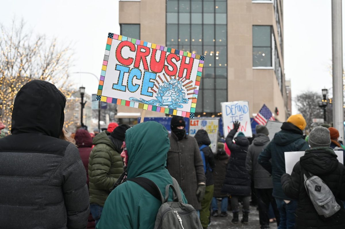 A sign held aloft by an attendee reads &ldquo;Crush ICE.&rdquo;