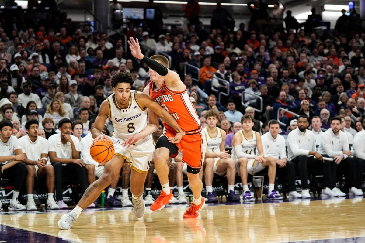 A basketball player crouches as they dribble and protect the ball from an opposing player.