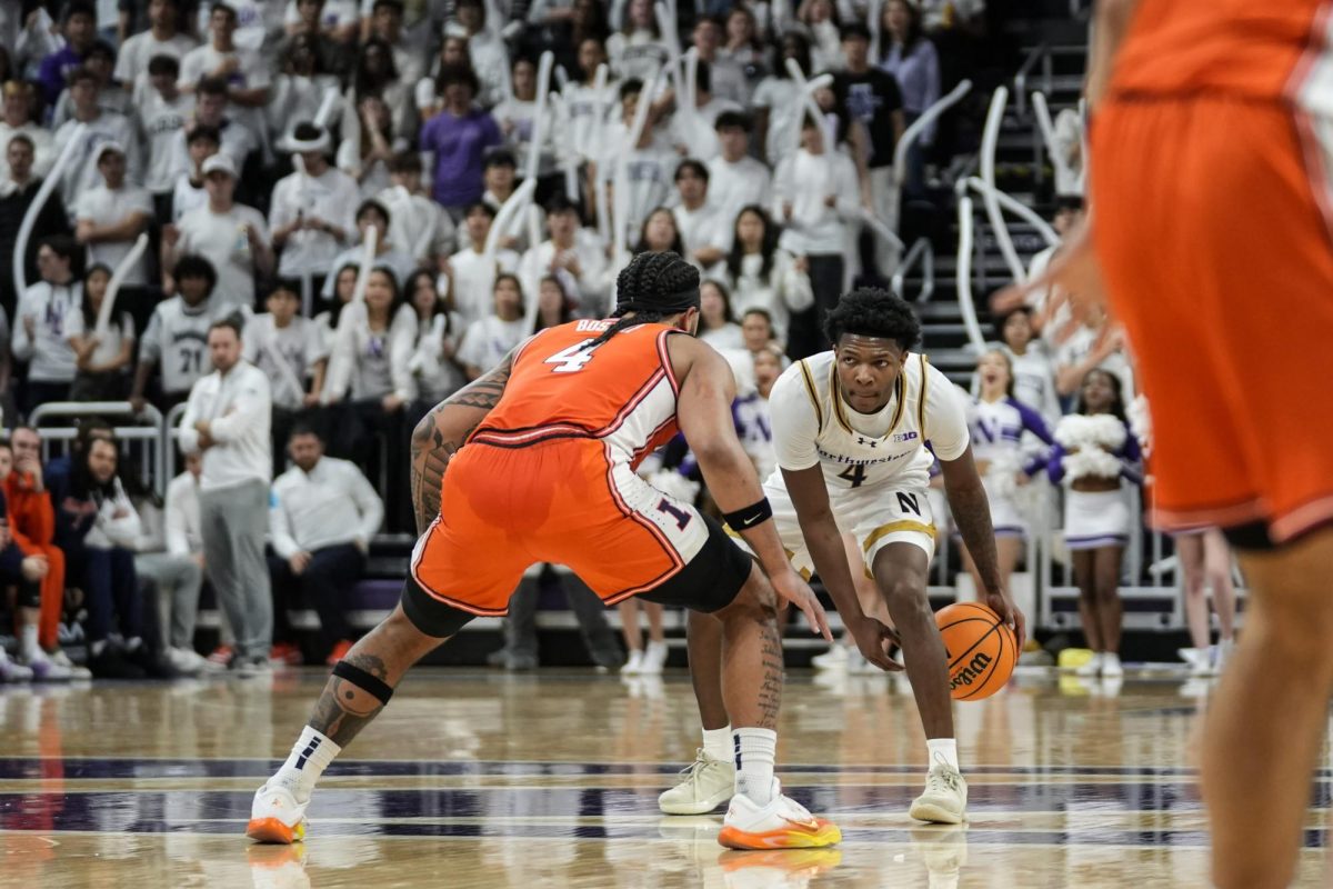 A basketball player dribbles low to the ground as an opposing player attempts to block them from passing the ball.