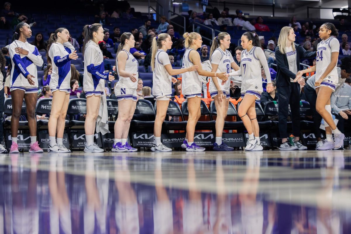 Northwestern players line up along the bench, exchanging high fives during a substitution break.