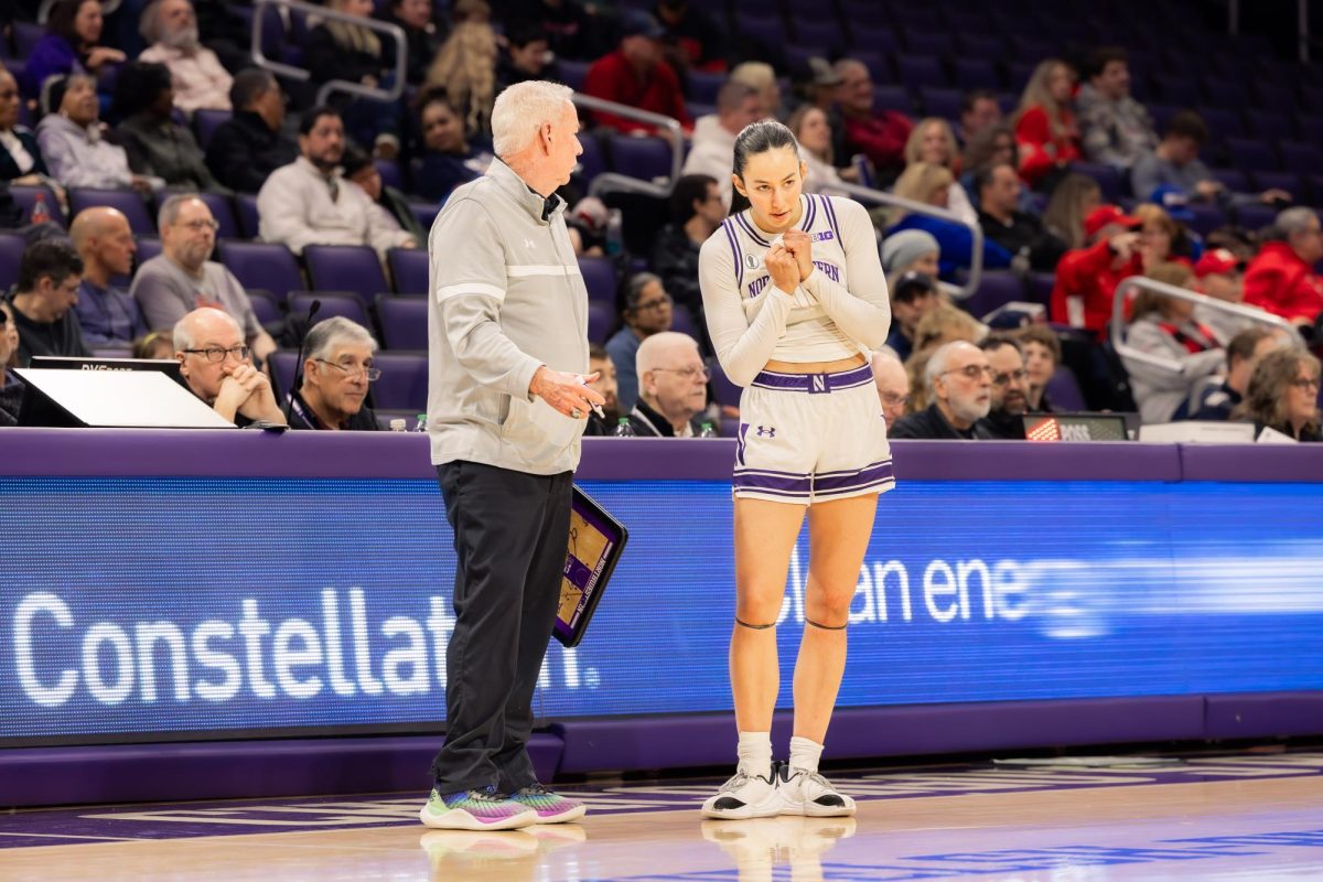 A Northwestern player listens to instructions from the head coach during a stoppage in play.