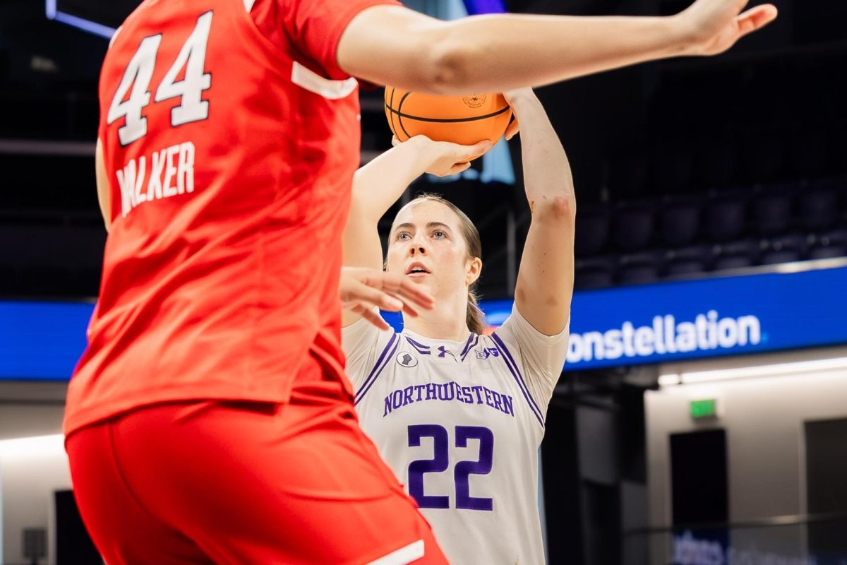 A Northwestern player releases a shot over a Rutgers defender with arms extended to contest.