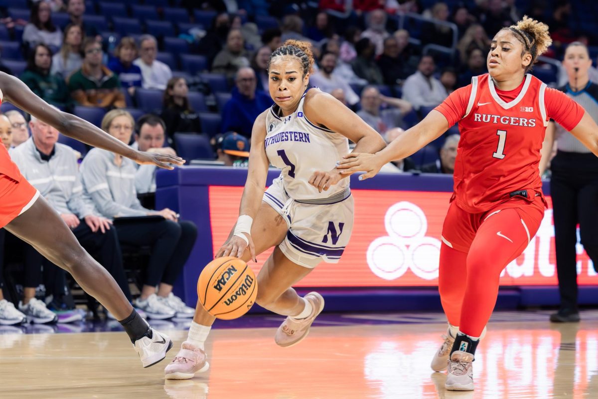 A Northwestern player drives toward the basket between two Rutgers defenders.