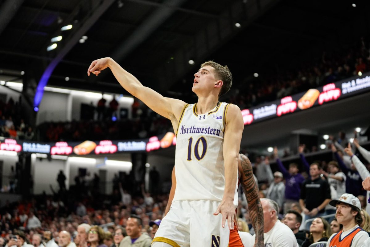 A basketball player stands with an arm raised after attempting a shot.