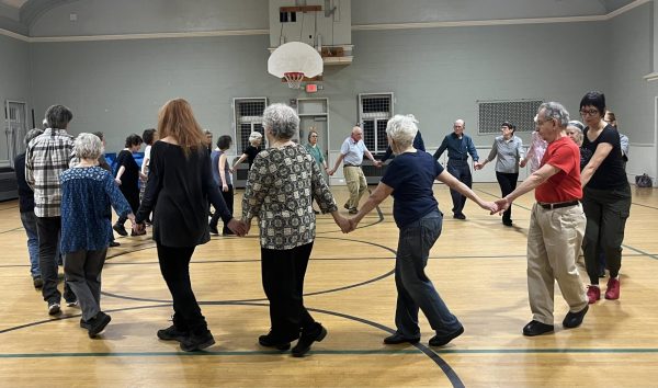 A group of people walk in a circle, hand in hand.