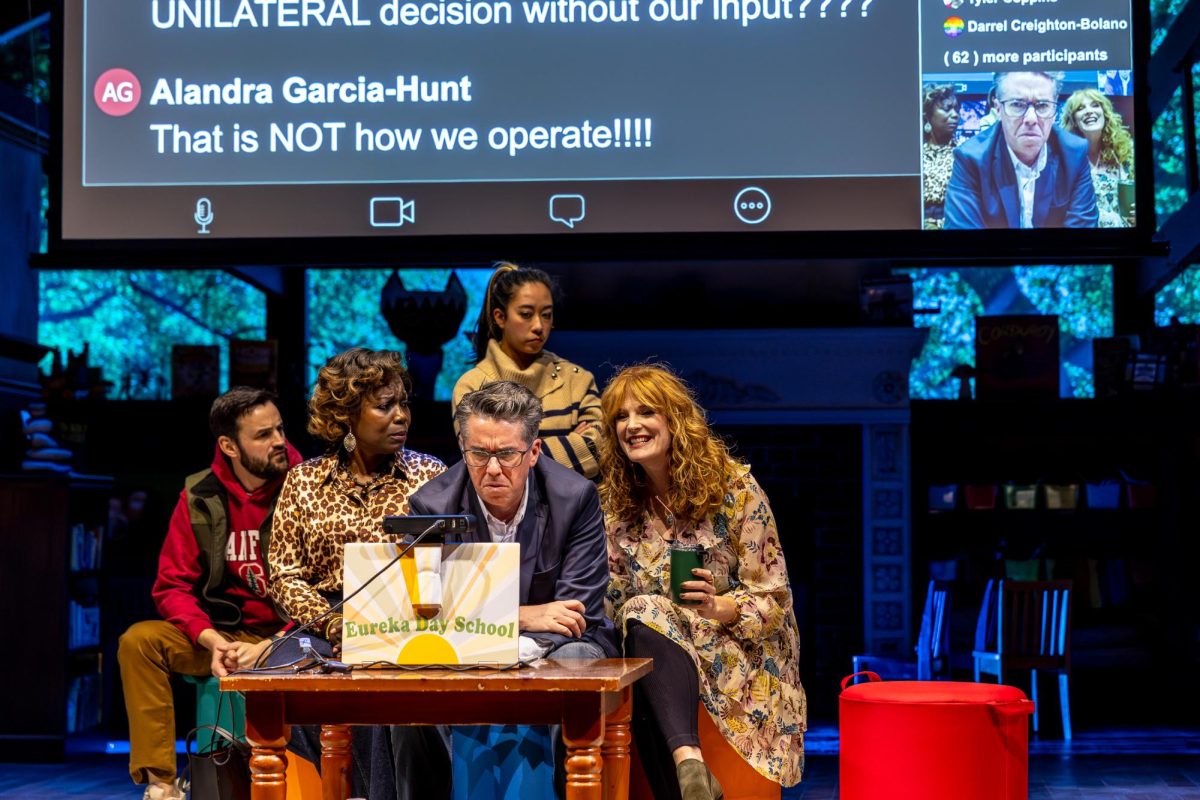 Five people cluster around a computer with a projected screen behind them.
