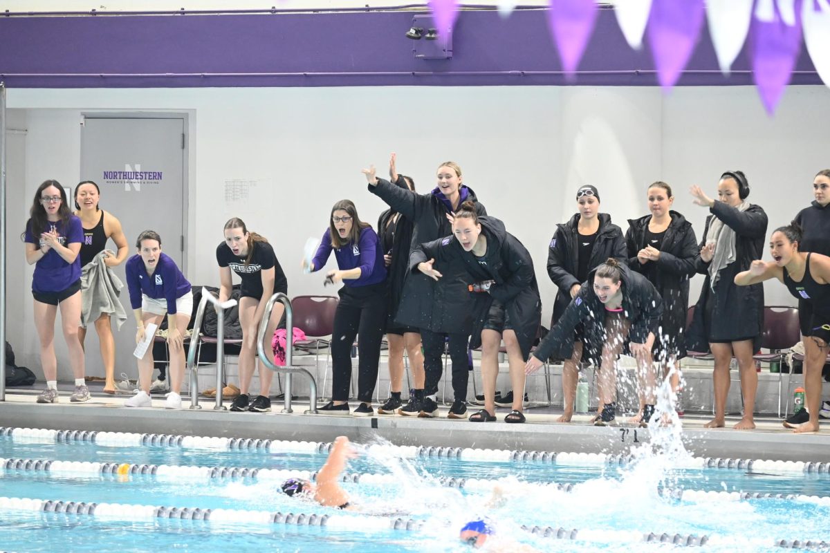 Claire and Lilly Mehok cheer on teammates from poolside in a dual meet earlier this season against Duke. 