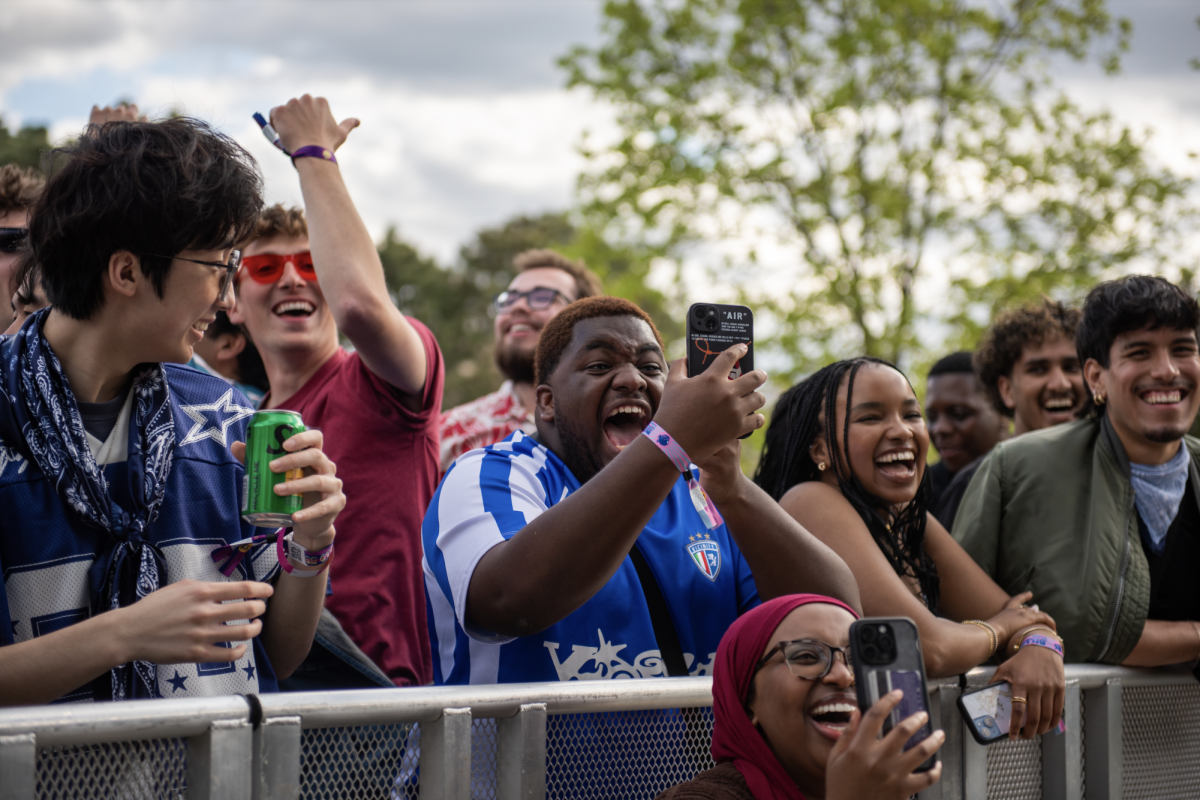 A crowd of students fills a barricade and enjoys a live performance.