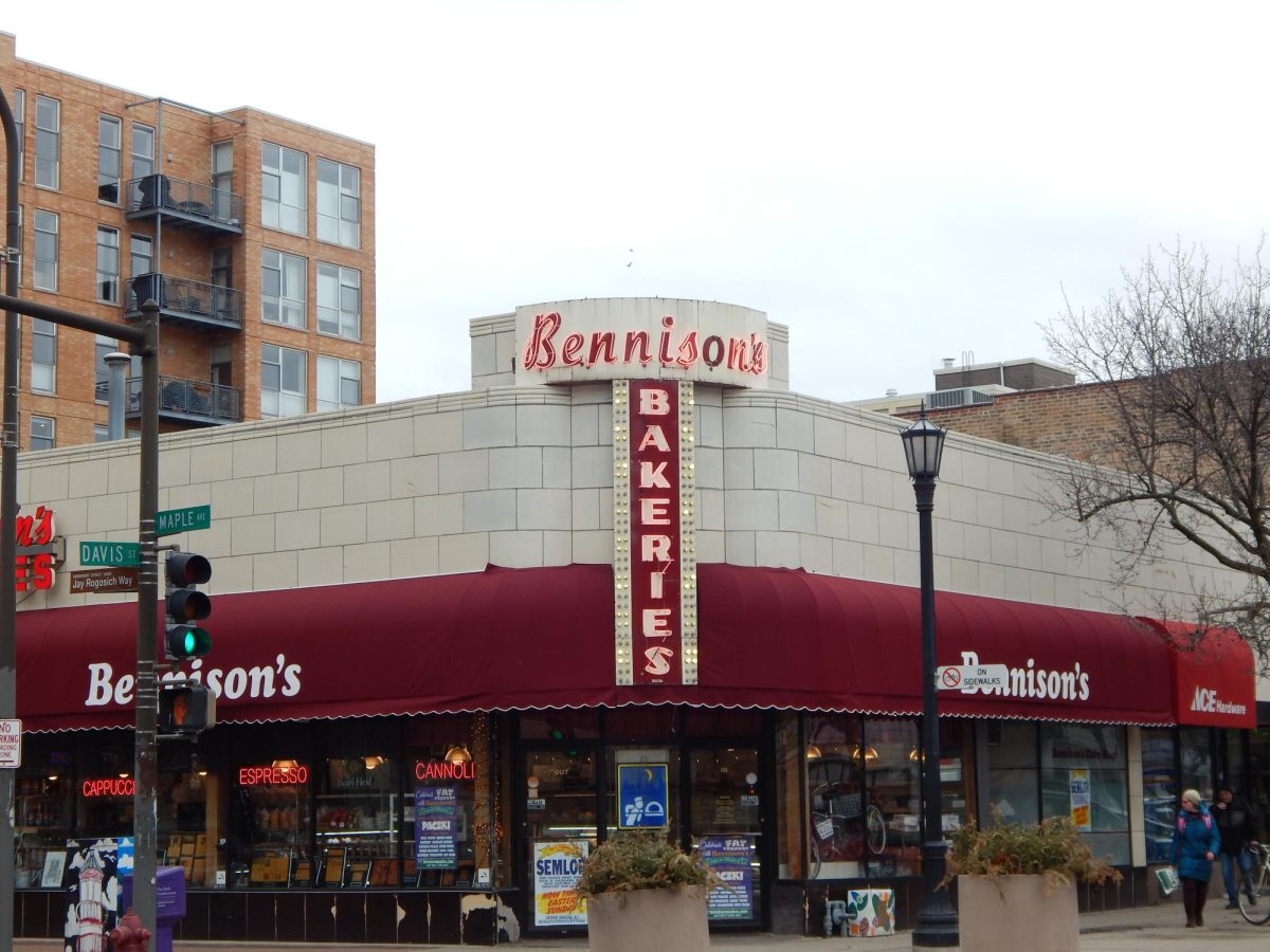The exterior of a storefront, with a red trimming surrounding the building and a neon red “Bennison’s Bakeries” sign.