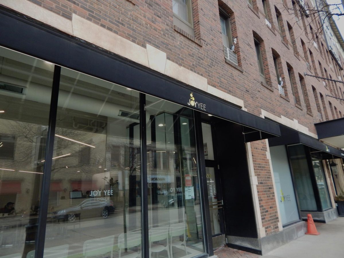 The exterior of a storefront with large windows. “Joy Yee” is branded on the trimmings above the storefront.