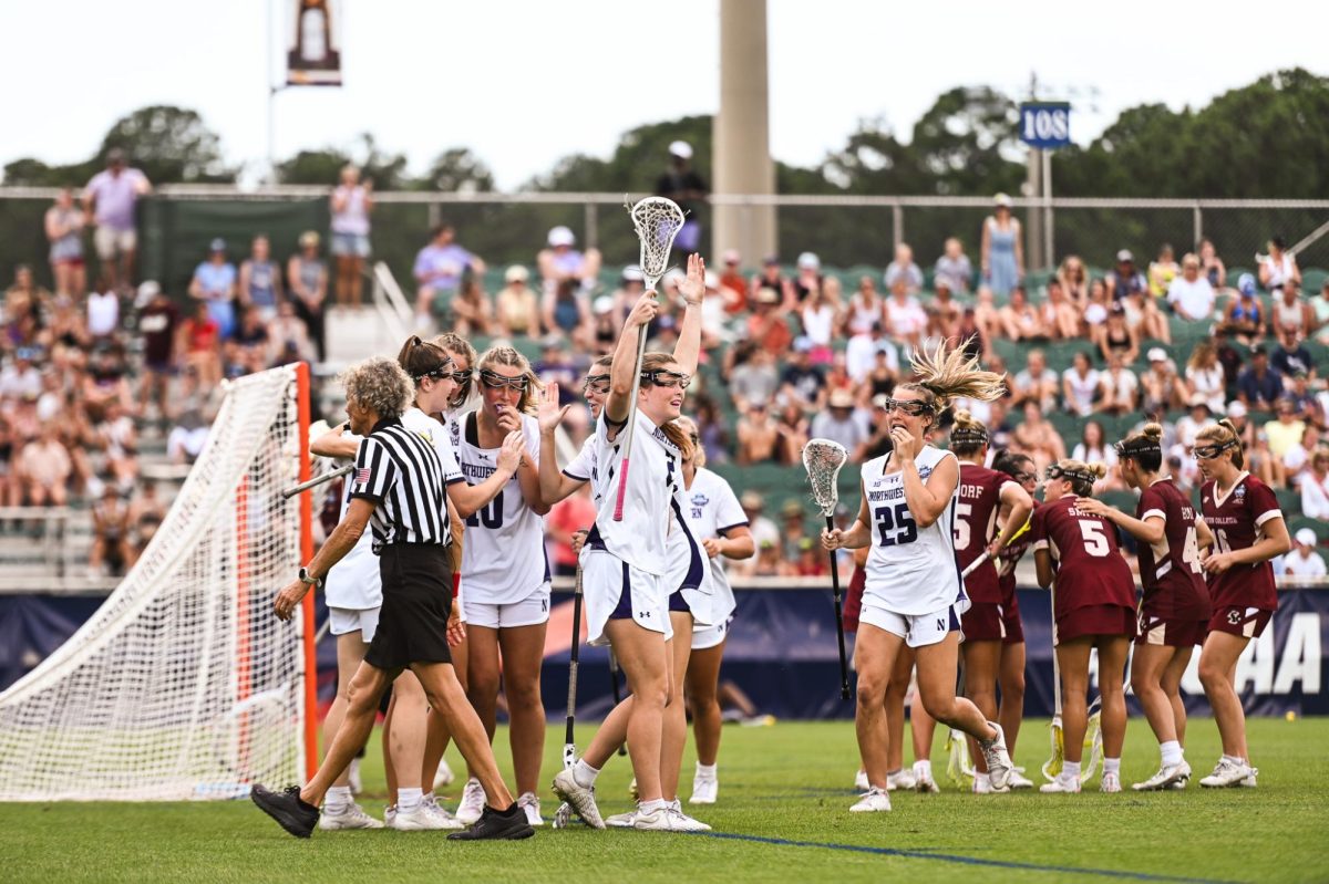 A player in a white jersey lifts their arms as other players huddle together.