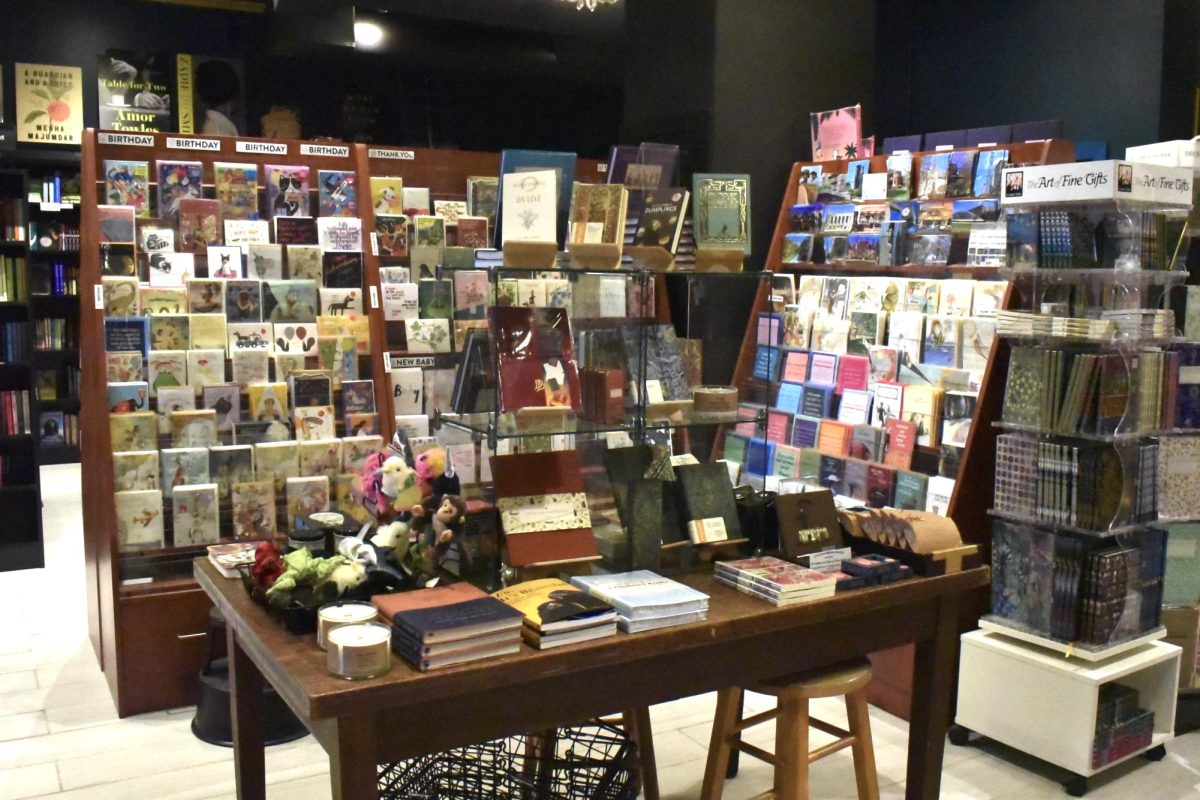 The table in the center contains a variety of colorful notebooks and the shelves behind the table show rows of cards.