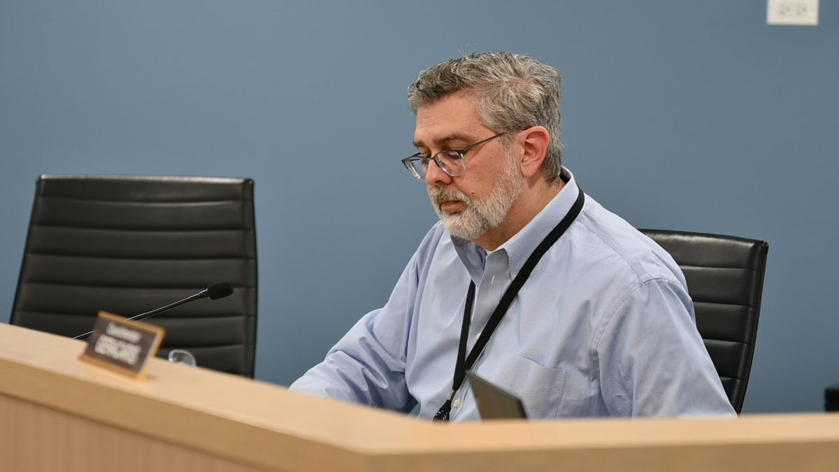 A seated person speaks into a microphone.