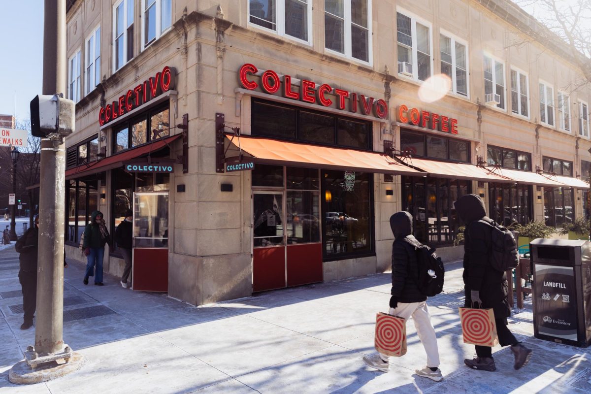 People carrying bags walking toward and entering a tan building featuring a neon sign that reads “Colectivo Coffee.”