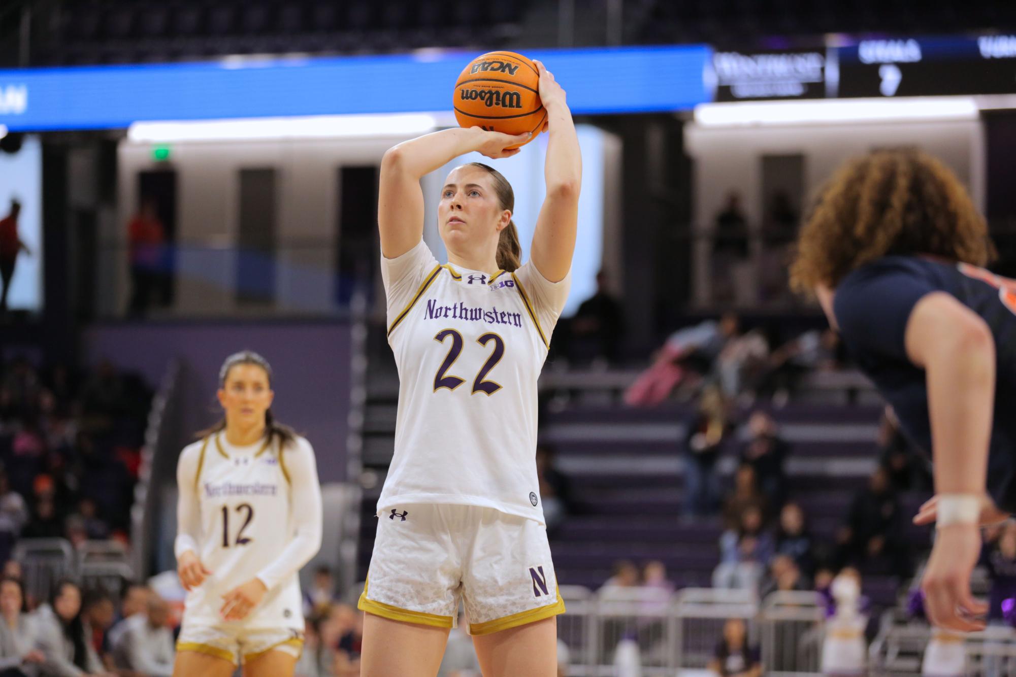 A person in a white jersey shoots a basketball.