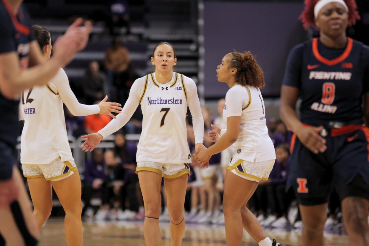 Two people in white jerseys high-five another person in a white jersey.