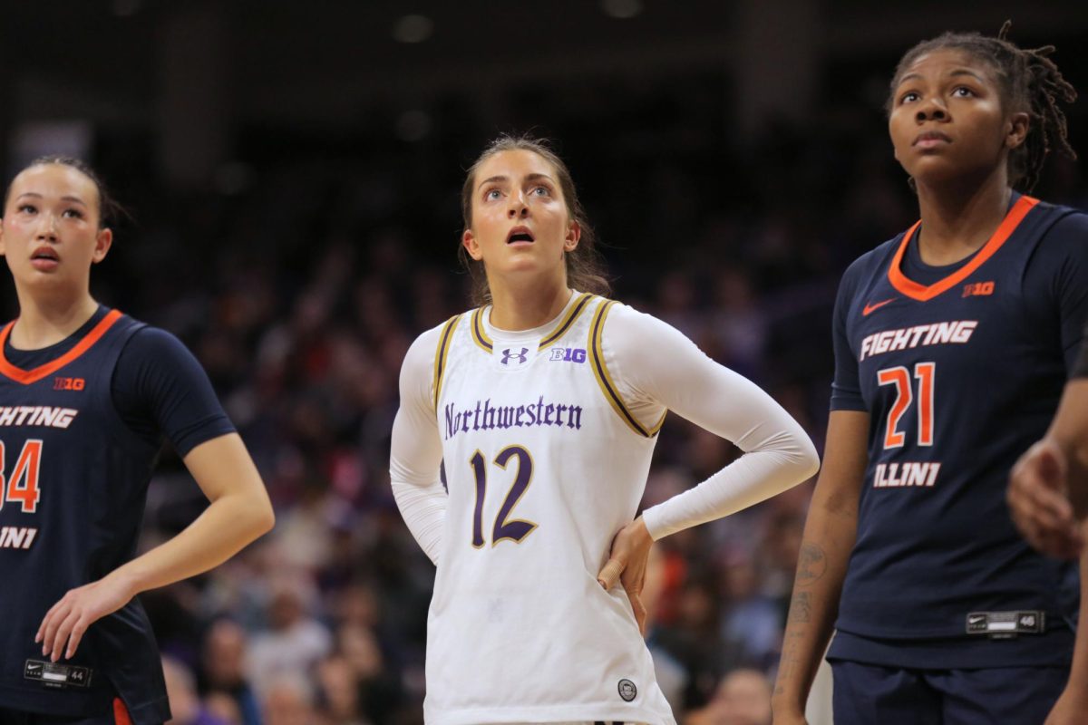 Two people in dark jerseys and one person in a white jersey look up.