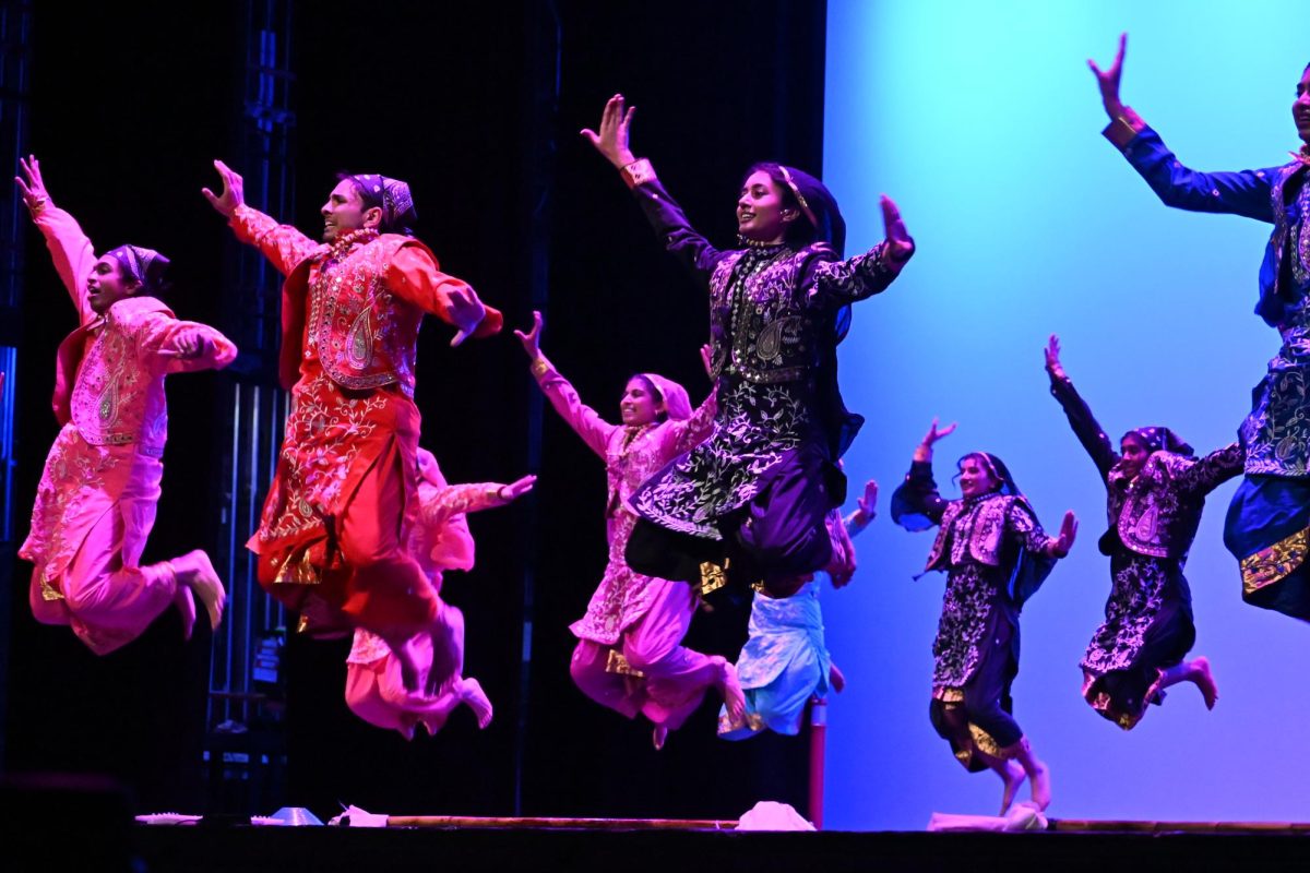 Dancers jump in the air simultaneously.