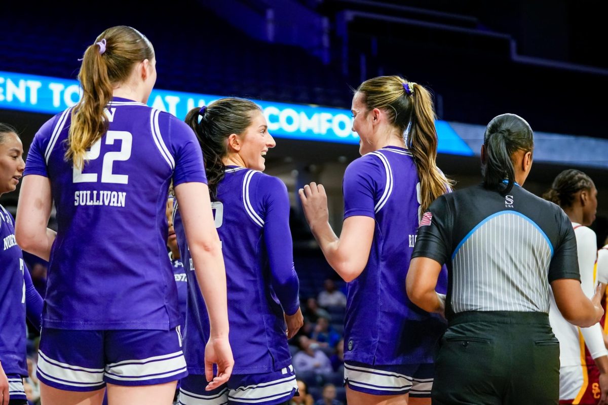 A group of basketball players stand together, smiling.