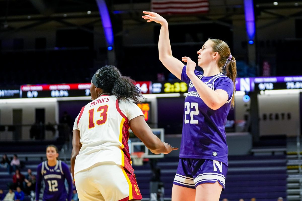 A basketball player has their arms raised after making a shot attempt.