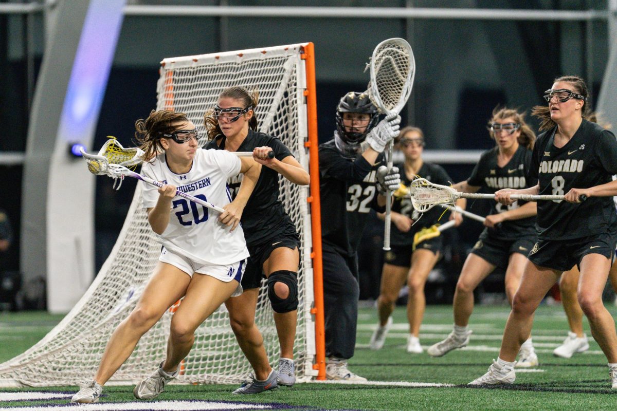 A lacrosse player takes the ball around the net while surrounded by opposing players.