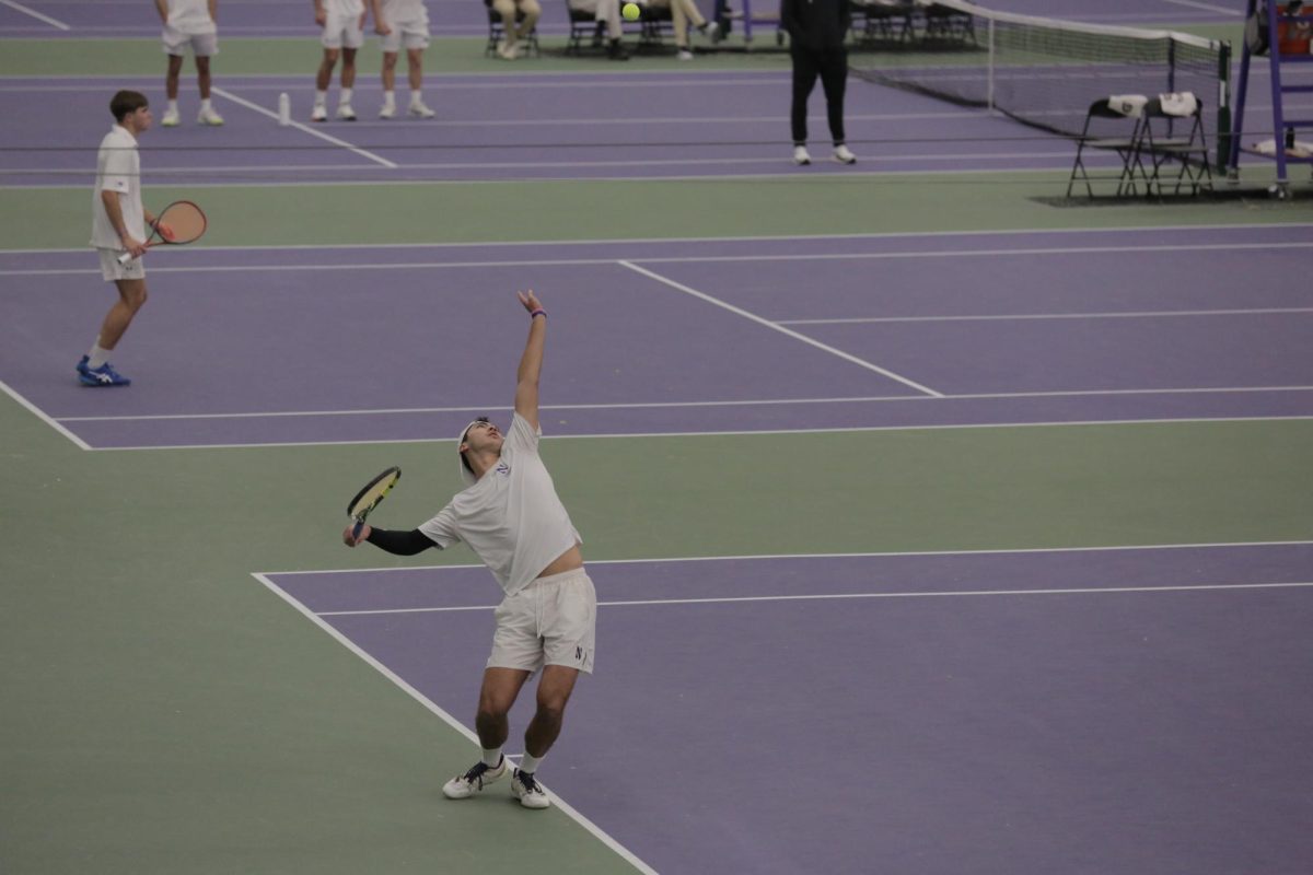 A person tosses the ball and begins a serve.