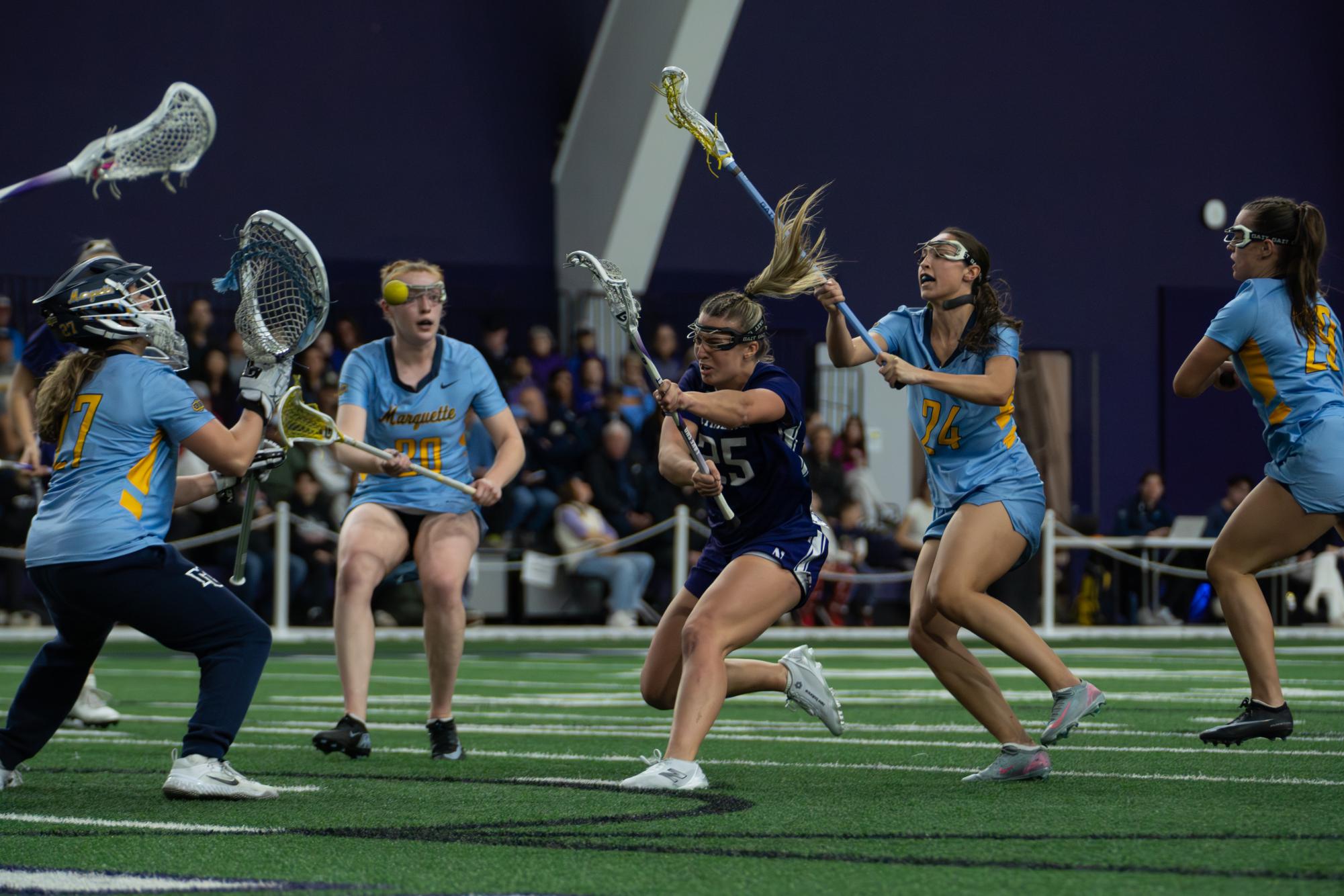 A player in a purple jersey shoots a ball past a goalkeeper in a blue jersey.