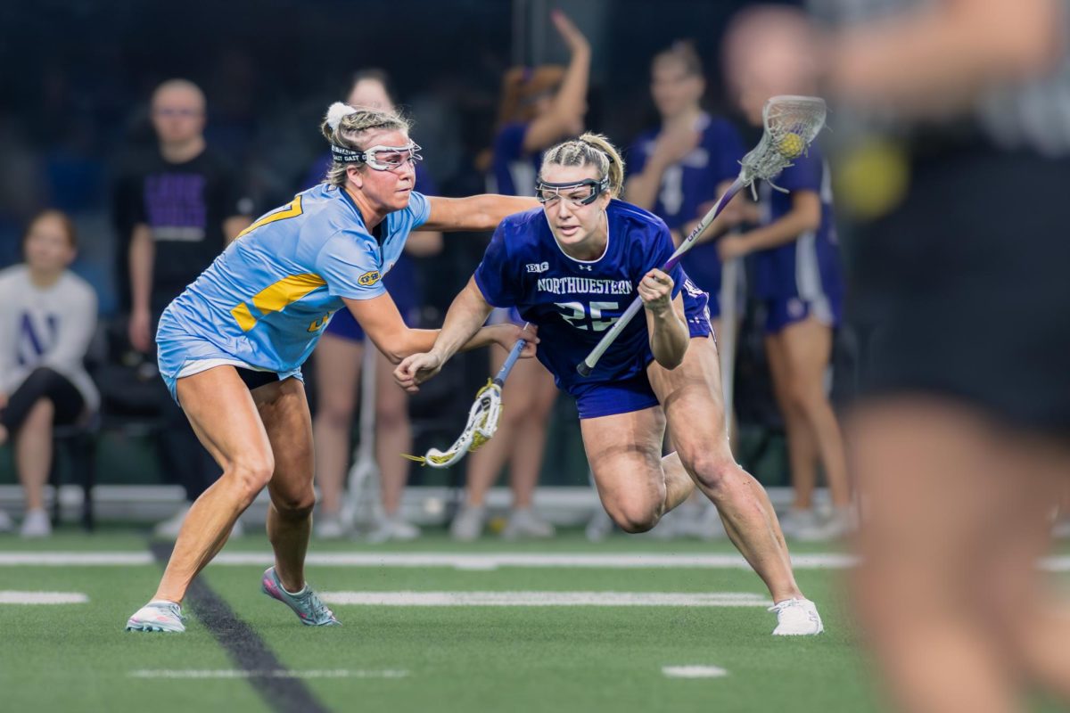 A Northwestern player runs around a defender while being pushed by their stick.