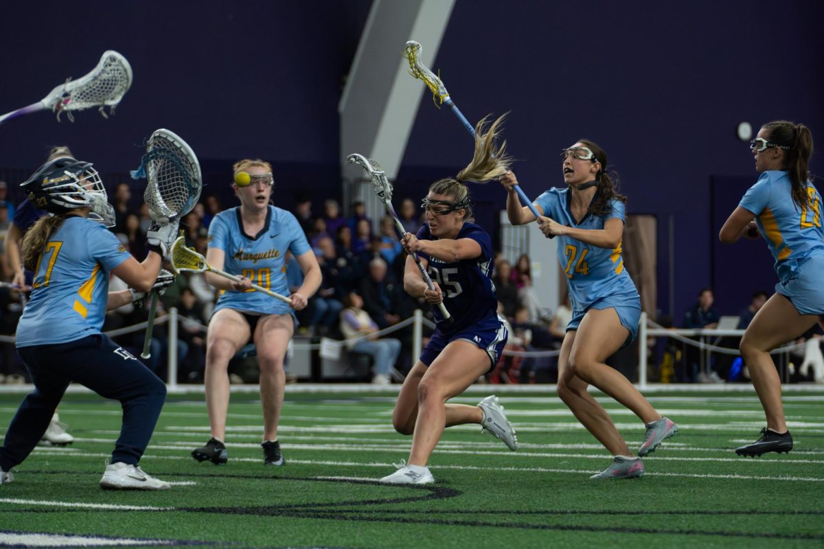 A player in a purple jersey shoots a ball past a goalkeeper in a blue jersey. 