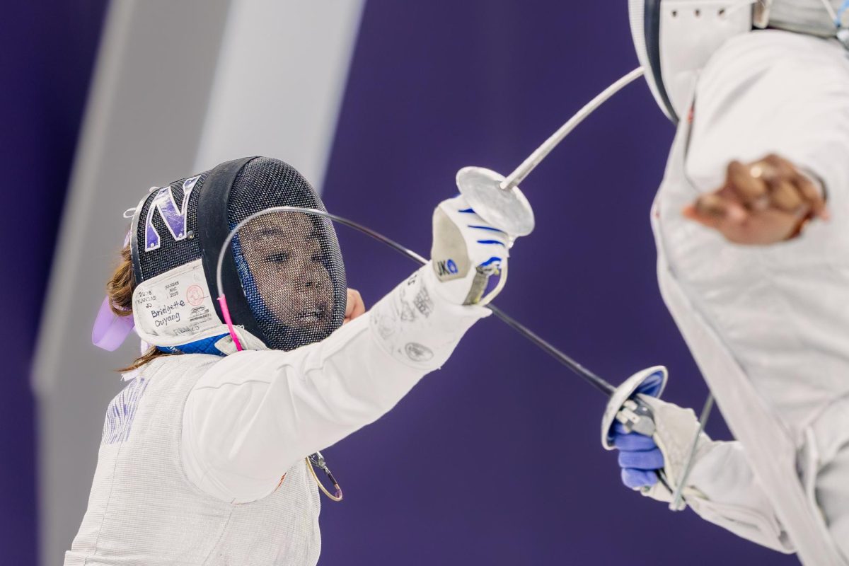 A masked fencer lunges towards their opponent.