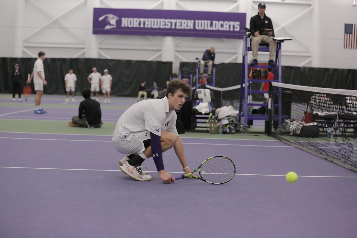 A person in a white shirt squats on a tennis court.